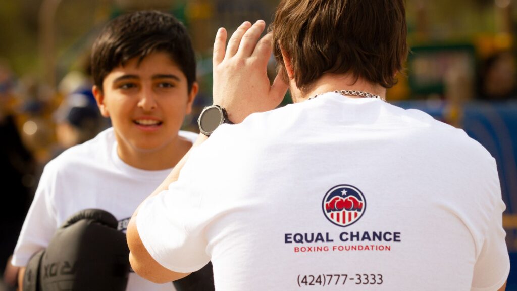 boxing coach teaching footwork to teenagers in open air
